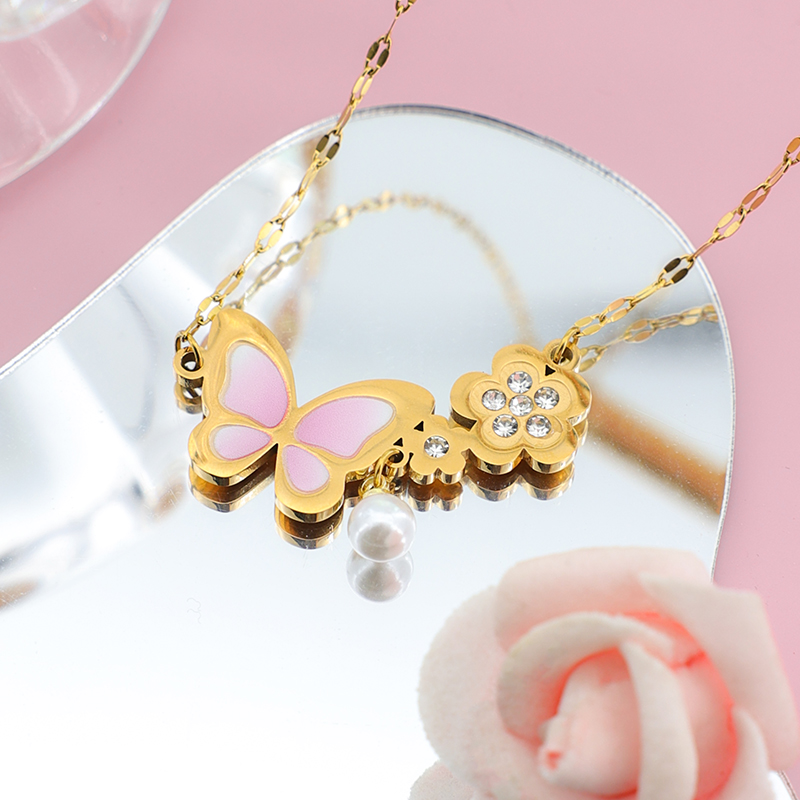 Aesthetic Reflection: Pink Butterfly & Pearl Necklace Heart-shaped mirror reflection of a pink enamel butterfly and flower pendant necklace with a dangling pearl.