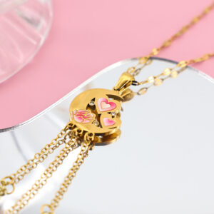 Gold crescent moon pendant with pink enamel heart and rose details, featuring small crystal accents.