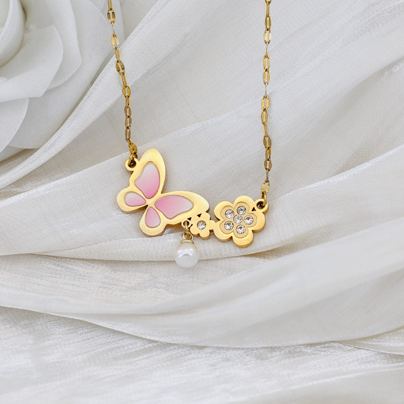 Craftsmanship Detail: Pink Butterfly & Crystal Flowers Detailed view of pink enamel butterfly wing and gold flowers with sparkling cubic zirconia centers.